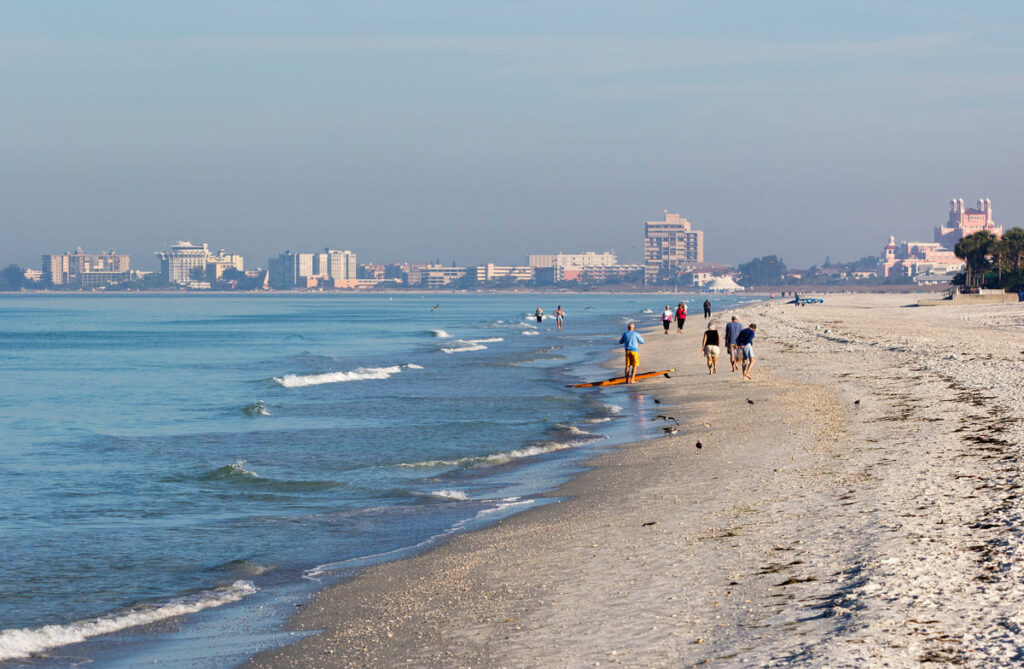 People walking in the surf on St. Pete Beach, Florida looking for shells